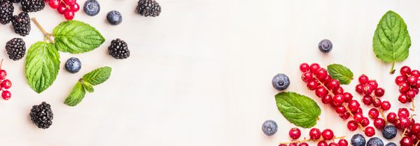 انواع توت های تابستانی تازه قاب های گوشه ای در پس زمینه چوبی سفید نمای بالا بنر برای وب سایت