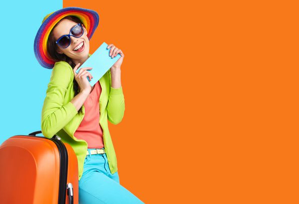 زن گردشگر با چمدان مسافرتی و کارت پرواز آبی جدا شده در پس‌زمینه تابستانی