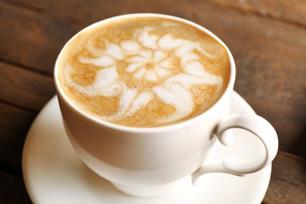 فنجان قهوه لاته آرت روی میز چوبی نمای نزدیک