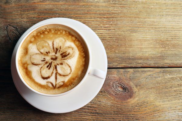 فنجان قهوه لاته آرت در زمینه چوبی