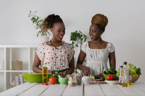 دو زن جوان آفریقایی در حال آشپزی غذای سالم - سالاد سبزیجات رژیم غذایی مفهوم رژیم غذایی سبک زندگی سالم آشپزی در خانه غذا آماده کن