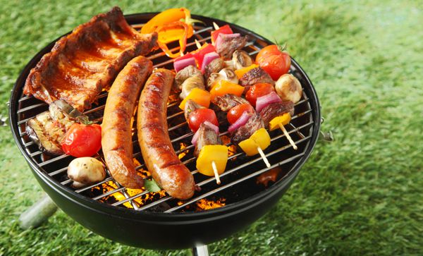 انتخاب کباب کردن گوشت روی زغال سنگ روی یک بیکیو قابل حمل با سوسیس های تند کباب گوشت گاو و قفسه های دنده در فضای باز روی چمن سبز با کپی