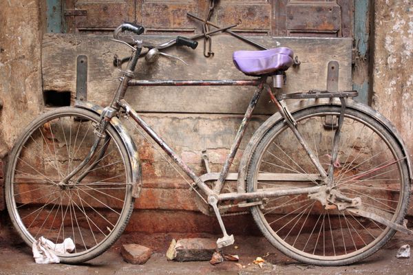 دوچرخه قدیمی در هند در دیوار پایه دوچرخه در وسط یک شهر باستانی با پوشش محافظ زین