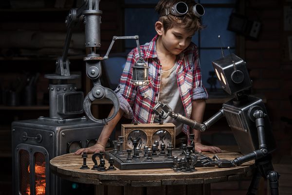 مکانیک پسر به نظر می رسد که دو ربات در عصر یک بازی شطرنج در استودیو انجام می دهند