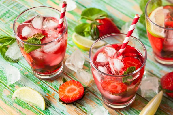 نوشیدنی تابستانی با طراوت با توت فرنگی در کوزه و لیوان روی میز چوبی قدیمی