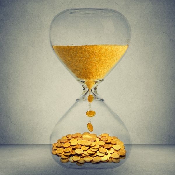مفهوم فرصت مالی زمان پول است ساعت شنی با گرد و غبار طلا و سکه های جدا شده در پس زمینه دیوار خاکستری