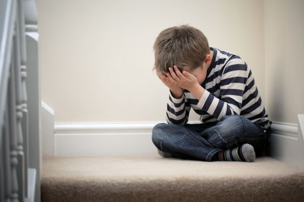 کودک مشکل دار ناراحت با سر در دست که روی راه پله نشسته است برای قلدری استرس افسردگی یا ناامیدی