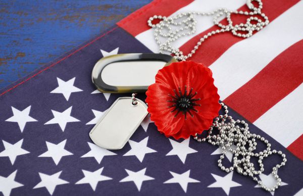 مفهوم روز یادبود ایالات متحده آمریکا با برچسب های سگ و خشخاش یادبود قرمز روی ستاره های آمریکایی و پرچم راه راه روی میز چوبی قدیمی آبی تیره