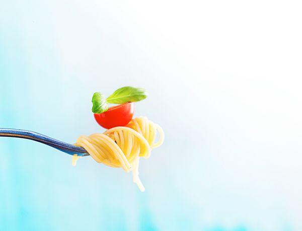 غذاهای ایتالیایی پاستا روی چنگال پاستا با روغن زیتون سیر ریحان و گوجه فرنگی اسپاگتی با گوجه فرنگی