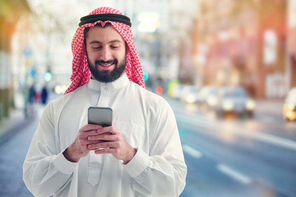 تاجر عرب در حال کار با تلفن خود در خیابان شلوغ در پس زمینه