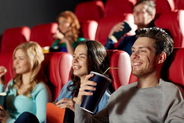 سینما سرگرمی و مفهوم مردم - دوستان خوشحال در حال تماشای فیلم در تئاتر