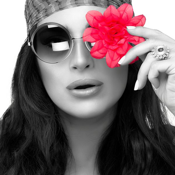 پرتره تک رنگ زن جوان شیک با استفاده از عینک گرد مد روز با گل صورتی در چشم و نگاه به دوربین