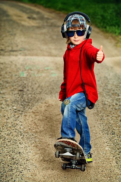 پسر بچه 7 ساله جالب با اسکیت بوردش در خیابان دوران کودکی تابستان