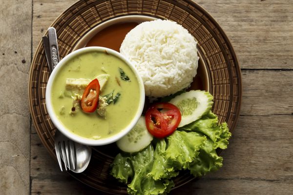 غذاهای تایلندی کاری سبز با برنج تزئین شده در زمینه چوبی