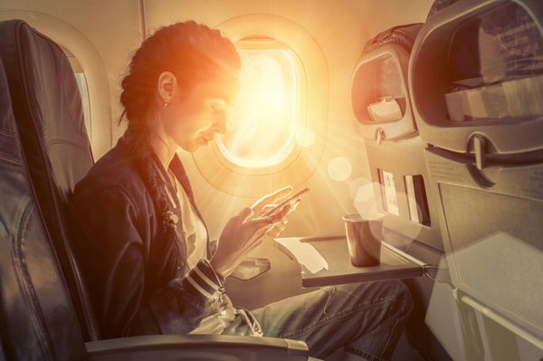 زن نشسته در هواپیما و به دنبال به تلفن همراه