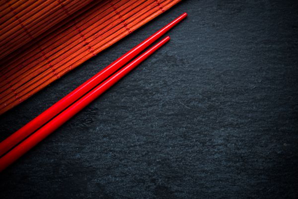 چینی های چینی قرمز ژاپنی و بامبو مات بر روی تخته سیاه پس زمینه منو