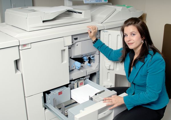 زن جوان در حال بررسی کاغذ در دستگاه زیراکس