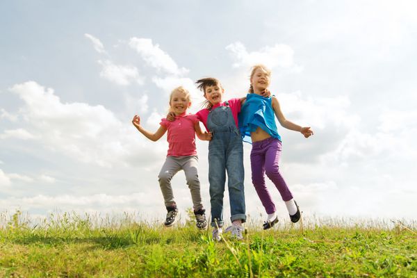 تابستان کودکی اوقات فراغت و مفهوم مردم - گروهی از بچه های شاد که در فضای باز در زمین سبز بلند می پرند