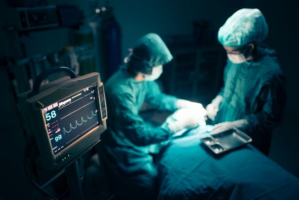 تیم جراحان با نظارت بر بیمار در اتاق عمل جراحی کار می کنند تمرکز انتخابی روی مانیتور