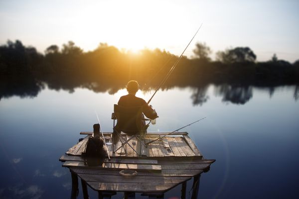ماهیگیر صبح زود در حال ماهیگیری در دریاچه ای است