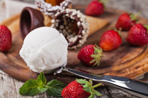 بستنی و توت فرنگی روی میز چوبی