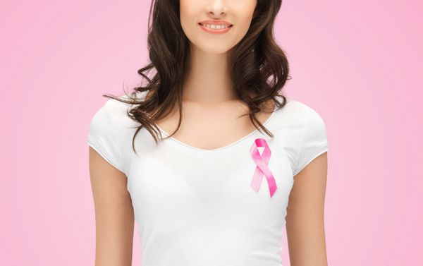 مفهوم مراقبت های بهداشتی مردم خیریه و پزشکی - زن جوان خندان با تی شرت با نوار آگاهی از سرطان سینه روی پس زمینه صورتی