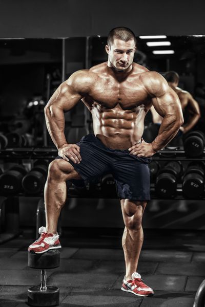 مرد بدنساز عضلانی ورزشکار عضلات خود را در باشگاه نشان می دهد
