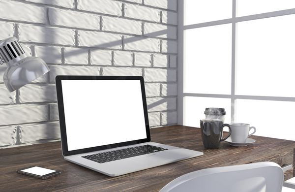 تصویر سه بعدی لپ تاپ و وسایل کار روی میز نزدیک دیوار آجری محل کار