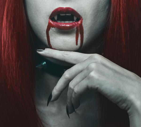 زن خون آشام زیبا لب های قرمز از نمای نزدیک در خون تم هالووین یا ترسناک