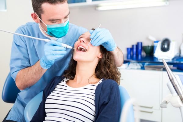 نمایی از یک زن جوان جذاب که توسط دندانپزشک درمان می شود
