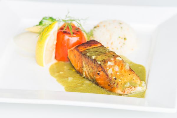 استیک ماهی قزل آلا در بشقاب سفید با برنج و سبزیجات - نقطه تمرکز انتخابی