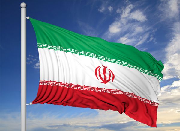 اهتزاز پرچم ایران بر روی میله پرچم در پس زمینه آسمان آبی