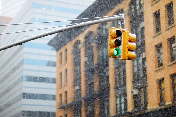 چراغ های راهنمایی شهر نیویورک با آسمان خراش ها در پس زمینه در هنگام بارش برف عظیم