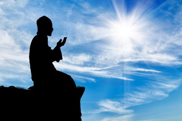 دین اسلام شبح مردی که در بالا در پس زمینه آسمان ابری نماز می خواند