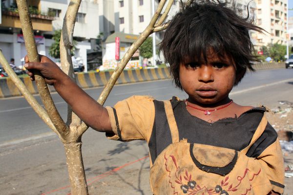 یک دختر گدای هندی که زیر آفتاب خشن کنار خیابان ایستاده است