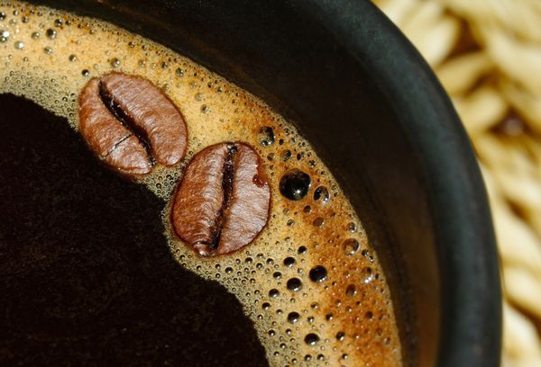 قهوه سیاه نوشیدنی معطر در یک فنجان با دانه های قهوه