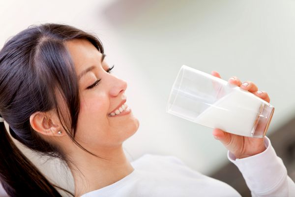 زن زیبا در حال نوشیدن شیر و لبخند زدن