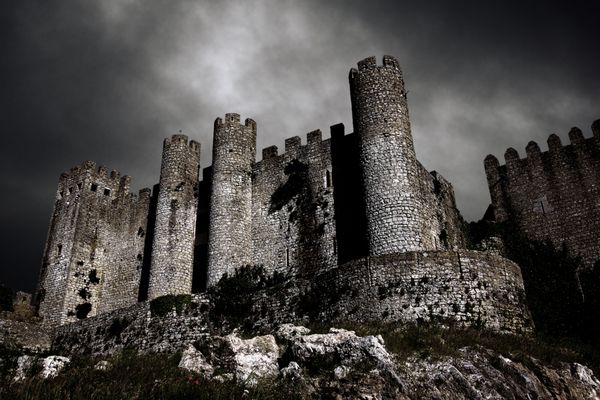 صحنه آزاردهنده با قلعه قرون وسطایی در شب با آسمان طوفانی