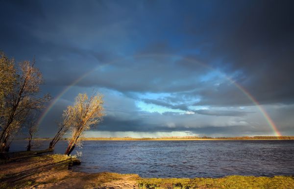 رنگین کمان کامل بر فراز رودخانه ob پس از باران شدید همراه با رعد و برق روسیه سیبری