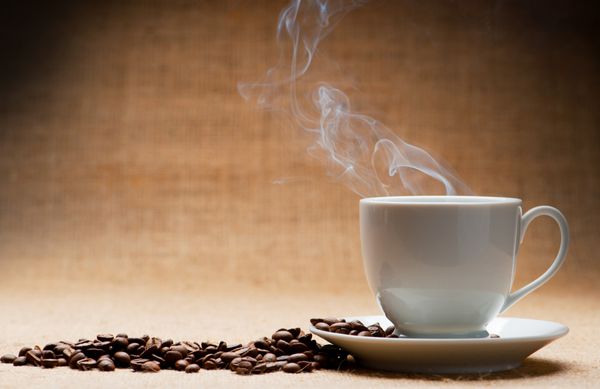 فنجان قهوه در مورد کشتی و دانه های قهوه در پس زمینه گرانج لحن قدیمی