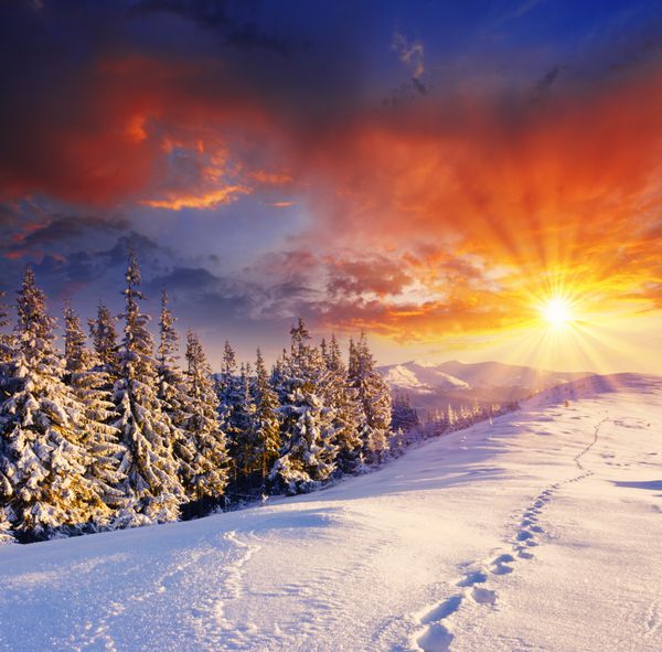 غروب باشکوه خورشید در چشم انداز کوه های زمستانی