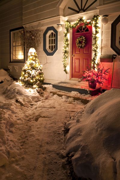 درب ورودی یک خانه خانوادگی پوشیده از برف که برای کریسمس تزئین شده است