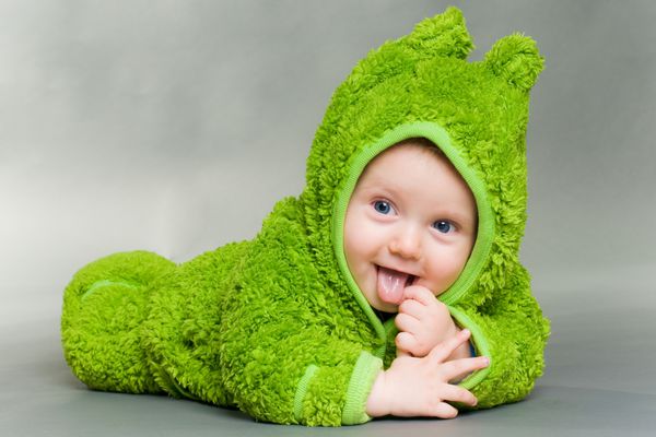 نوزاد ناز شیرینی که در کت و شلوار قورباغه ای پوشیده شده است