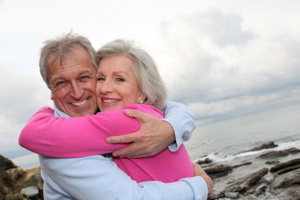 زوج سالمند شادی که در کنار دریا یکدیگر را در آغوش گرفته اند