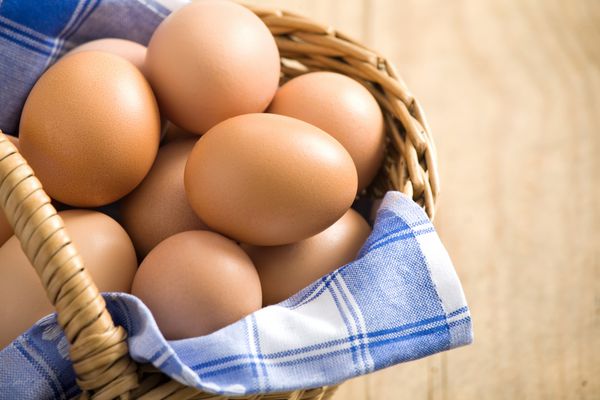 تخم مرغ عید پاک در یک سبد با پارچه آبی همه روی میز چوبی