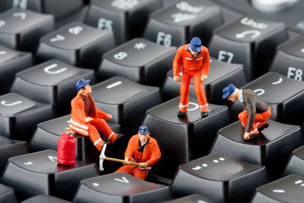 مجسمه های کوچک کارگرانی که صفحه کلید کامپیوتر را تعمیر می کنند