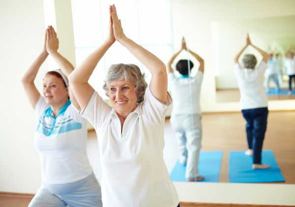 پرتره دو زن سالخورده در حال انجام تمرینات یوگا در سالن ورزشی
