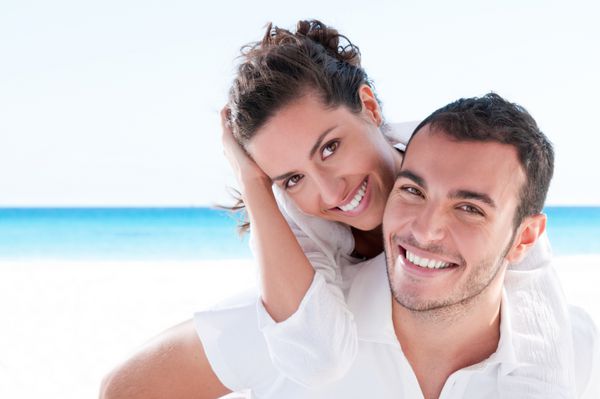 زن و شوهر جوان خندان در ساحل زیبای تابستانی