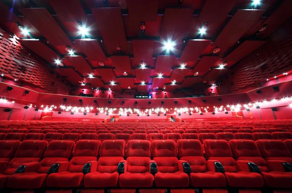 نمای کم زاویه سقف و ردیف صندلی های قرمز راحت در سینمای اتاق قرمز روشن