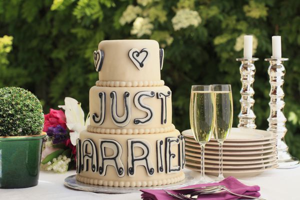 کیک عروسی مجلل و دو لیوان فلوت شامپاین روی میز پذیرایی